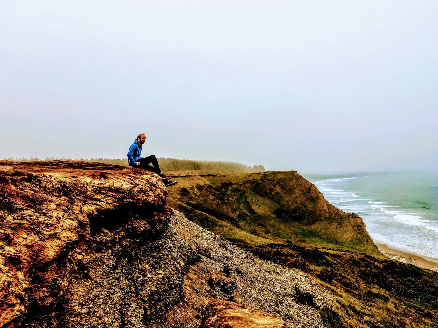 Dylan sitting on a bluff overlooking the Oregon coastline